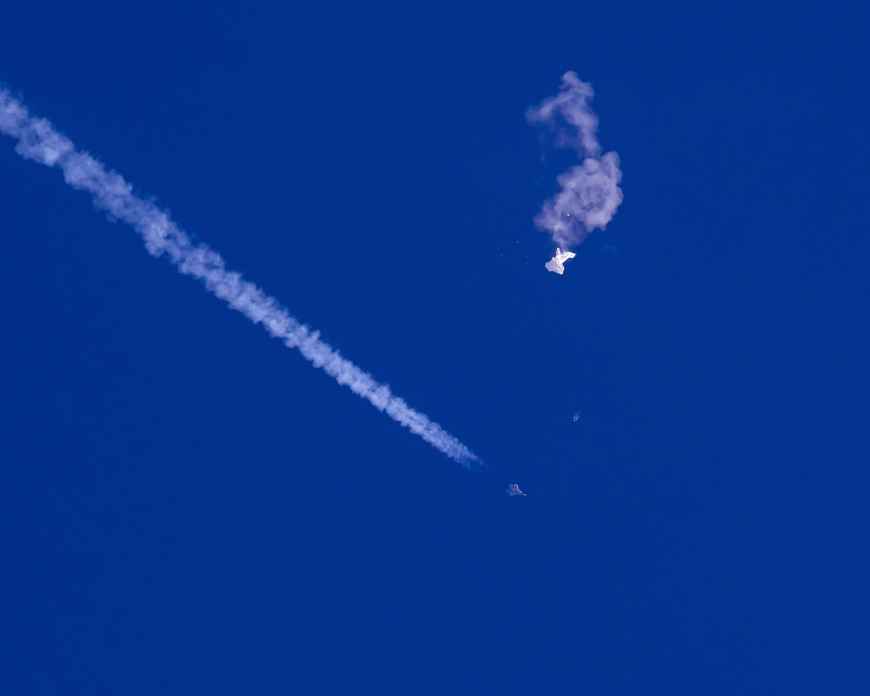 Blauer Himmel mit einer kleinen F22 mit Kondensstreifen und dem zerstörten Ballon